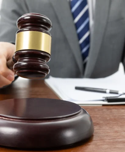 closeup-shot-person-with-gavel-hand-papers-table