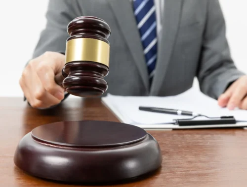 closeup-shot-person-with-gavel-hand-papers-table
