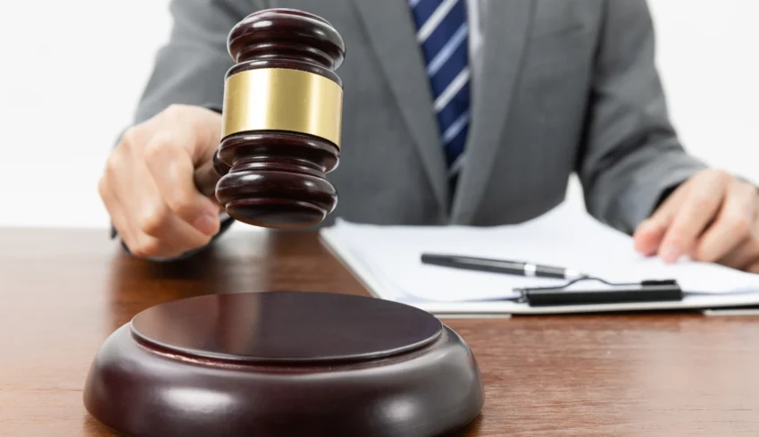 closeup-shot-person-with-gavel-hand-papers-table